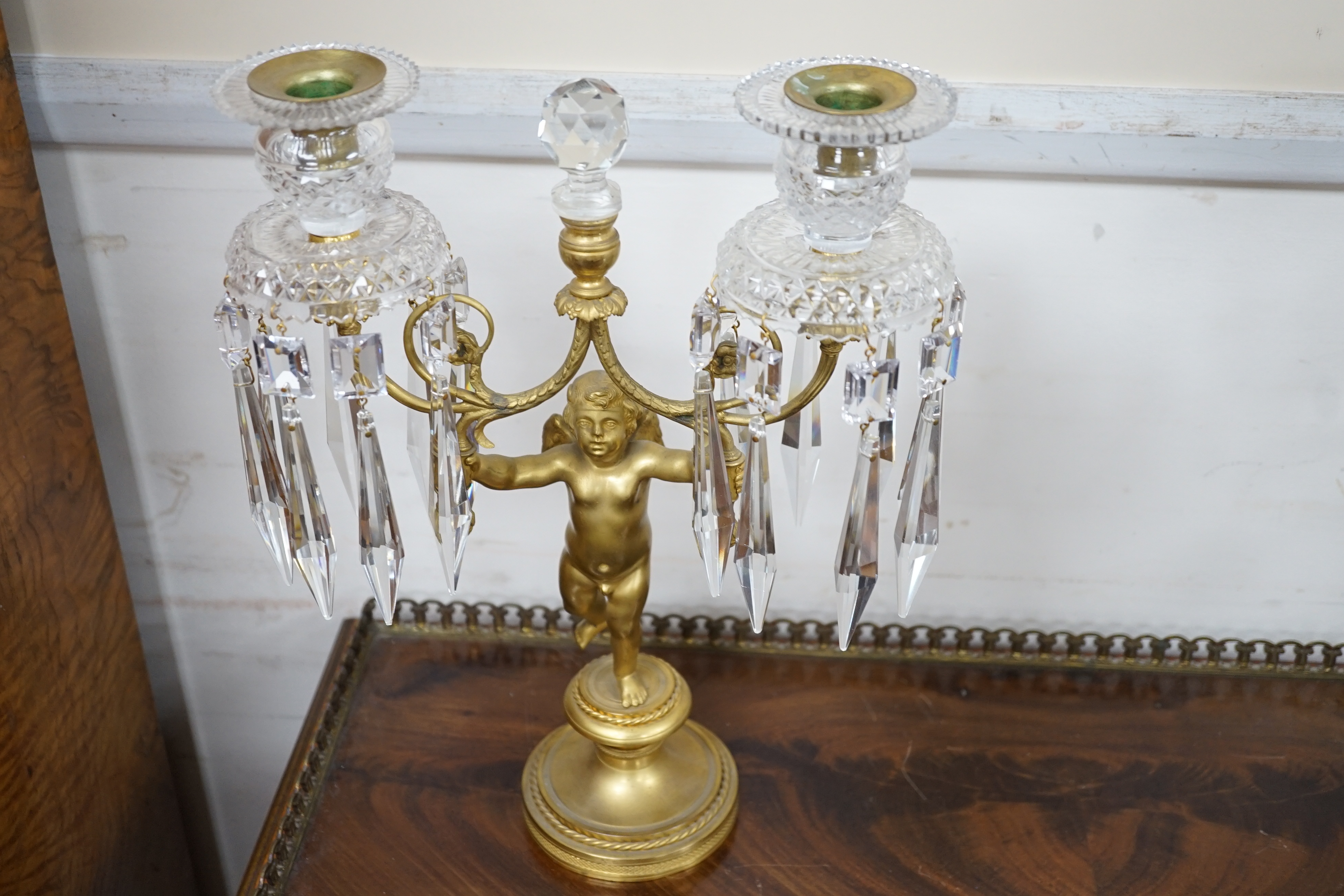 A pair of Regency ormolu ‘Cupid’ two branch glass lustre candelabra, 37cm high